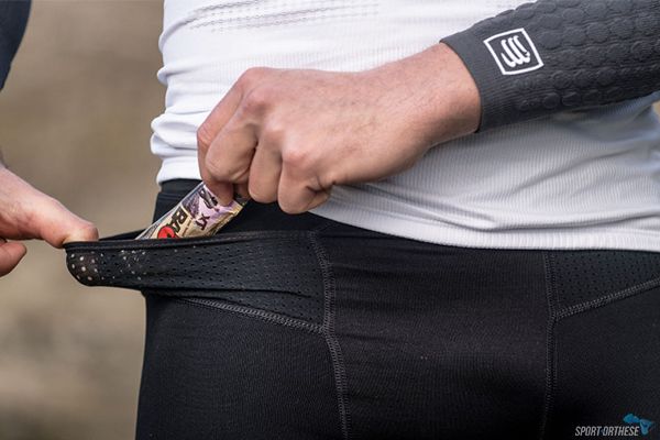 personne mettant à manger dans la petite pochette du pantalon pour courir