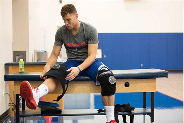 joueur de basket mettant les genouillère de cryothérapie