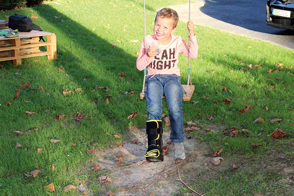 enfant avec une botte de marche pediatrique jouant dehors